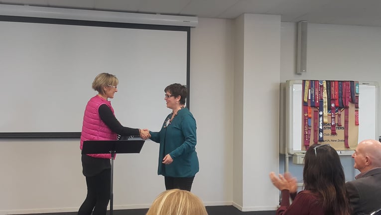 Two women in front of an audience, shaking hands