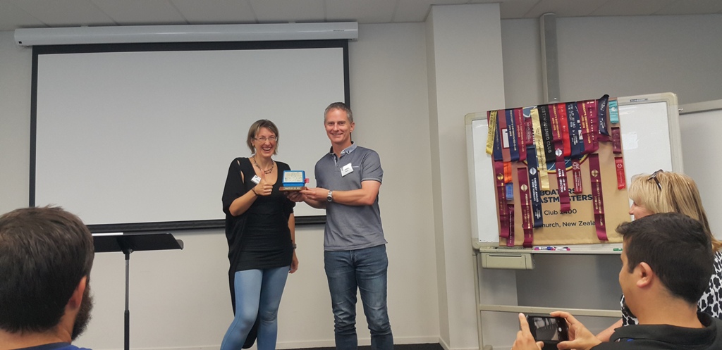 sabine presenting aaron with an award facing a seated audience