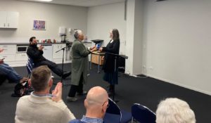 Two women in front of an audience, one receiving an award