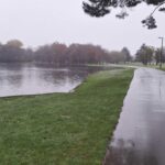 A large pond and a shiny footpath on a rainy day
