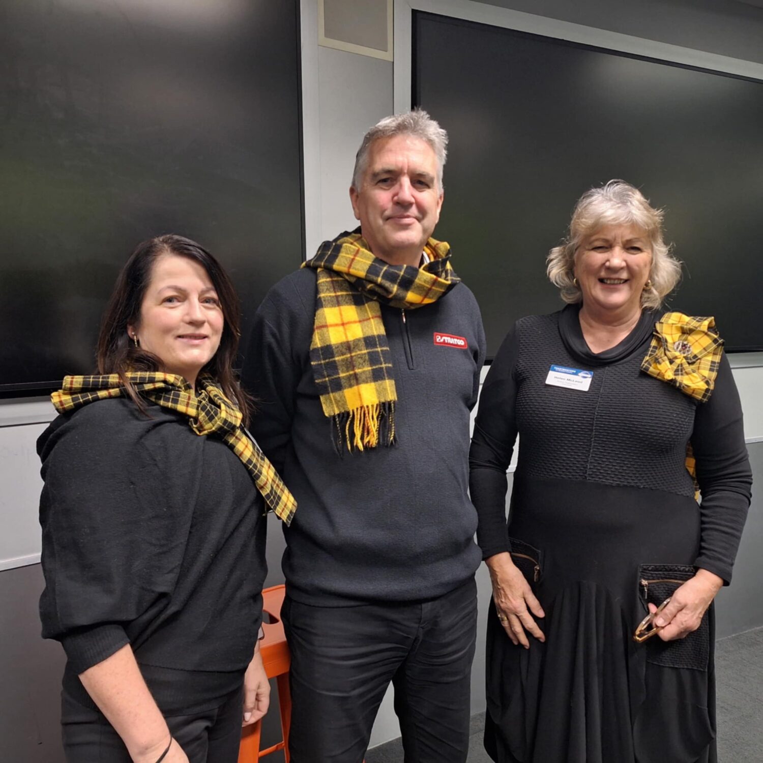 2 women and a man, wearing black and yellow tartan representing their McLeod clan.