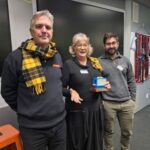 2 men being presented the plastic toaster award by a woman.