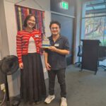 Woman giving the Toastie Award to a man for his Ice Breaker Speech Story